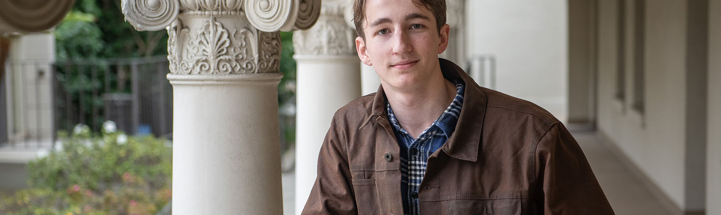 Will McMillan from the waist up in front of Greek columns on campus