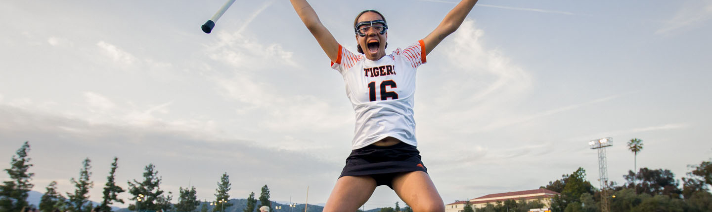 An Occidental College lacrosse player jumps into the air joyfully after a team victory