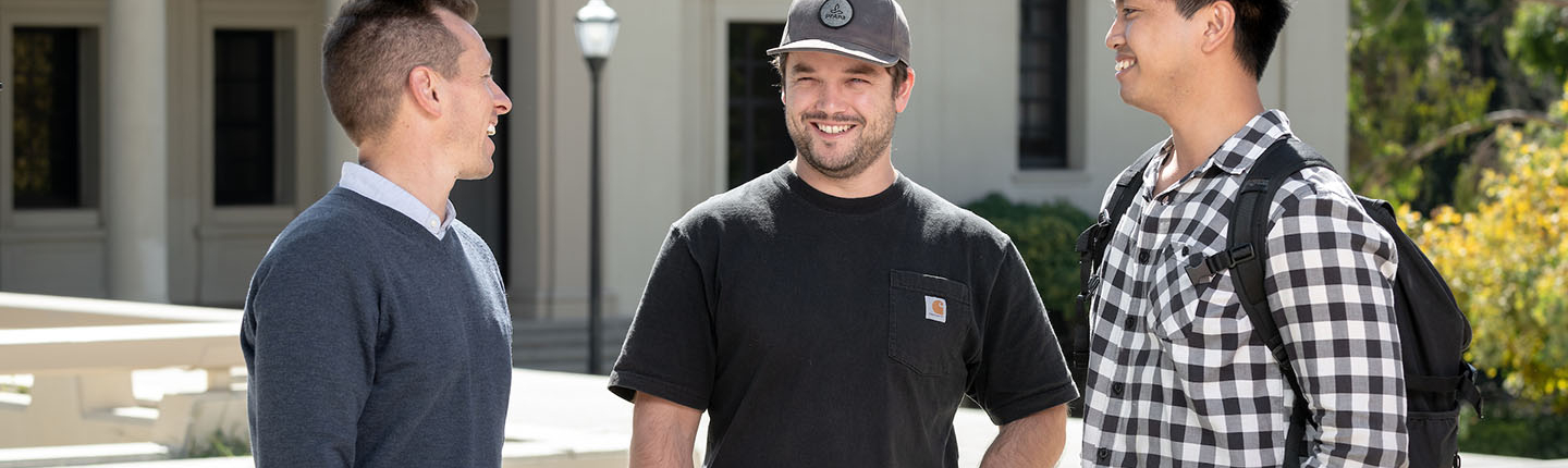 Three Occidental College veteran students stand together, talking and laughing