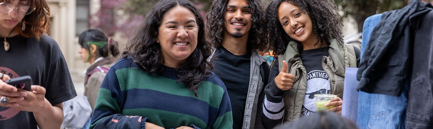Three Occidental students standing together and smiling warmly