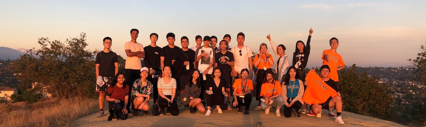 a group of Occidental College students standing together, smiling at sunset