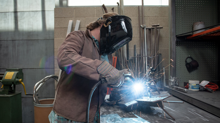 An Occidental (Oxy) student welding in a workshop