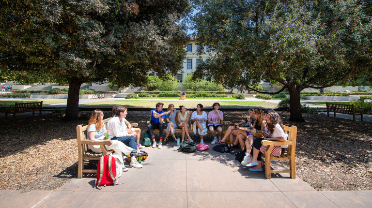 A group of Oxy students lined up on three benches facing each other on the Quad