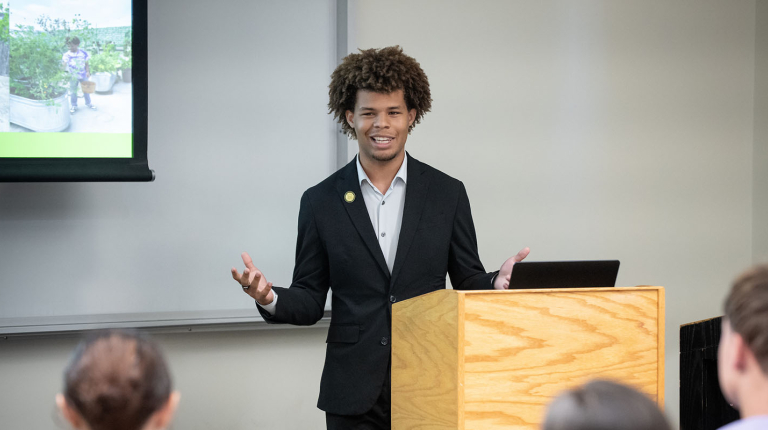 Jaymes Griggs presenting at a lectern at the Summer Research Program conference on the Occidental campus.
