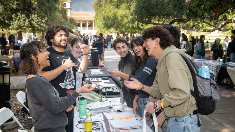oxy students at a table at the involvement fair on the quad smiling and laughing