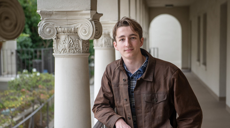 Will McMillan from the waist up in front of Greek columns on campus