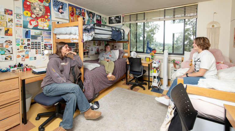 three students chatting together in a decorated dorm room