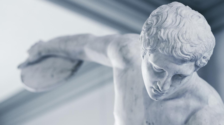 An ancient Greek or Roman sculpture of a man with his arm stretching back to throw a discus, representing the Classical Studies program at Occidental College (Oxy).