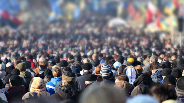 rear view of a large crowd of people viewing international flags