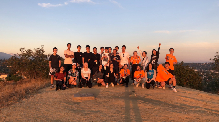 a group of Occidental College students standing together, smiling at sunset