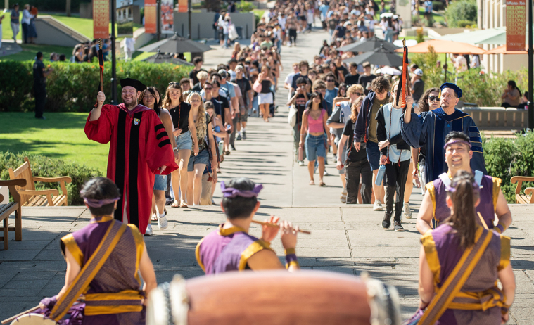Two long lines of students walking up to Thorne Hall on campus for Convocation