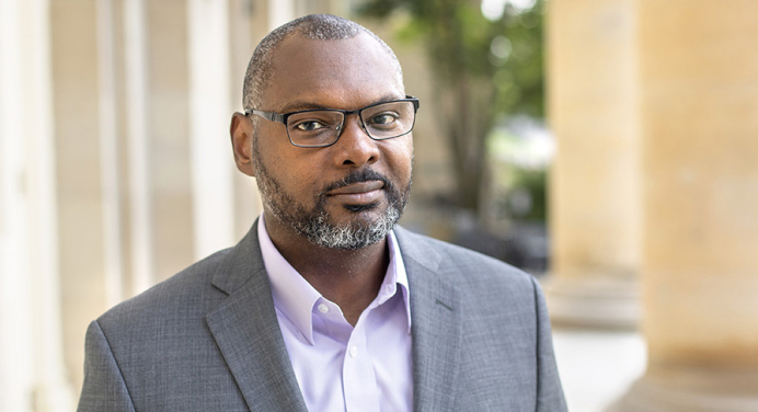 Professor Derrick Spires headshot with glasses and grey coat