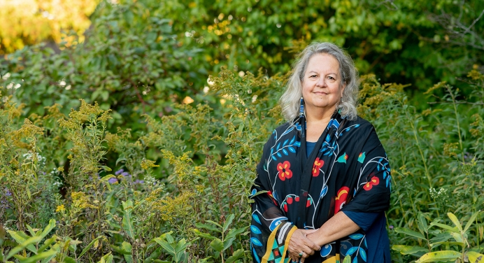 Robin Wall Kimmerer photographed outdoors in front of a green setting with wildflowers
