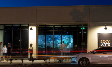 People stand in front of the Oxy Arts building at night, wit