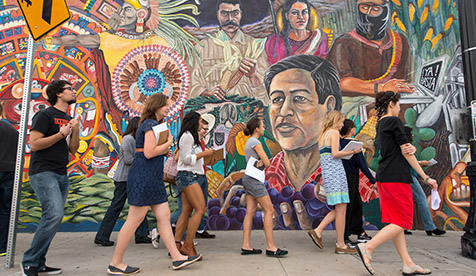 people walking past a significant Chicano mural