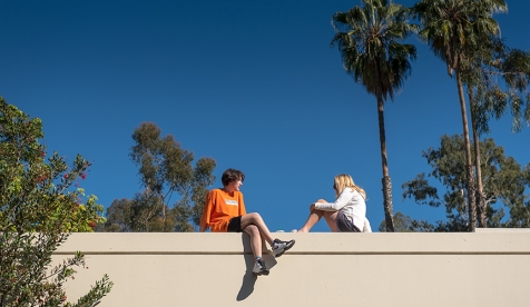 Two Occidental College students sit on a wall on the Los Angeles campus