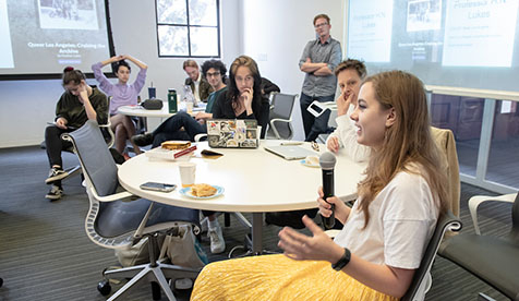 Occidental CTSJ students sitting at a round table in discussion. One student is holding a microphone.