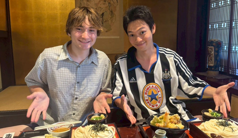 Oxy student Charlie Carver in Japan with a friend at a table covered with food