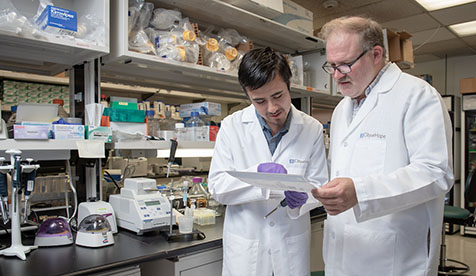 Oxy student and professor in a laboratory reviewing documents together