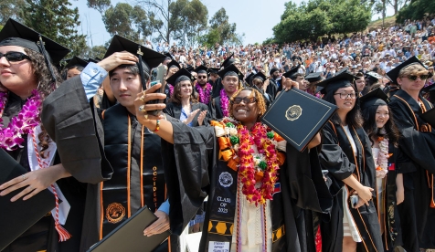Proud graduates holding up their degrees on Commencement Day