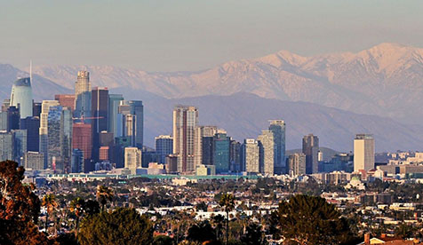 Los Angeles skyline against mountains with trees in foreground