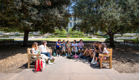 A group of Oxy students lined up on three benches facing each other on the Quad