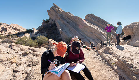 Occidental (Oxy) Students sitting in front of a rock formation taking notes