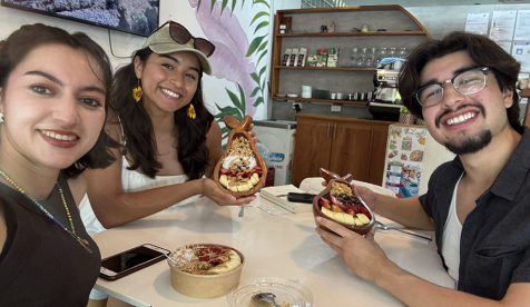 Three Oxy student sitting at a table eating a meal and smiling at the camera