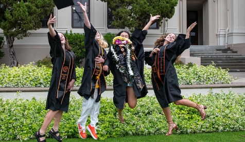 a group of new Occidental graduates jumping into the air with their caps