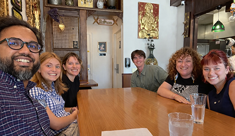 A group of Occidental (Oxy) students seated around a wooden table smiling at the camera