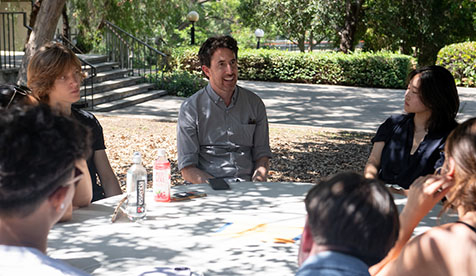 A group of Occidental (Oxy) students and a professor seated outdoors in duscussion