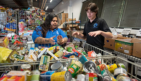 Two people sorting through donated food items at a food bank or pantry