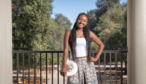 Occidental Student posing for photo on the Los Angeles Campus holding a Frisbee overlooking the Quad