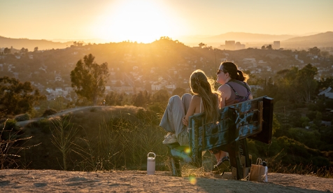 Two Occidental students sit on a bench at the top of Fiji Hill above the college campus in Los Angeles