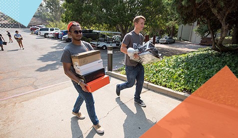students carrying boxes on campus