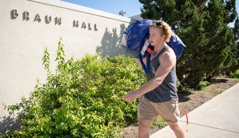 an Occidental student carries his duffel bag into the Braun Residence Hall