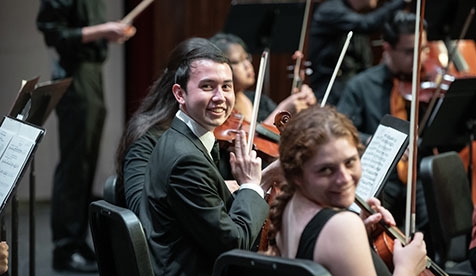 Members of the student orchestra smiling with their instruments