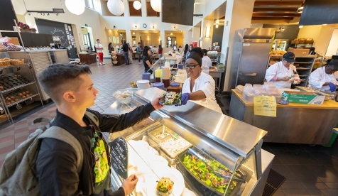 A student accepts a plate at the dining hall salad bar