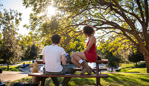 Two Occidental (Oxy) students seated at a table studying on the campus quad