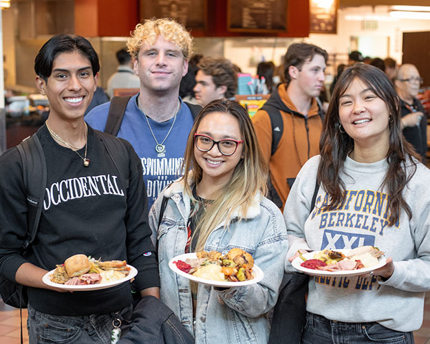 Four Occidental students standing together, holding their food plates in the Marketplace