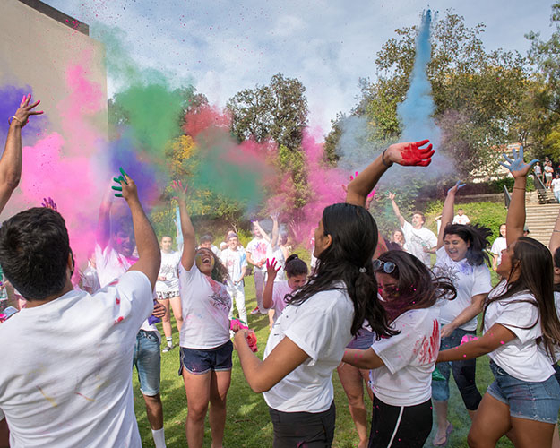 Occidental students throwing colorful powder into the air for a Holi celebration