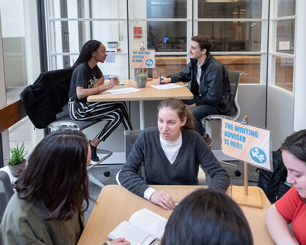 Oxy students seated at tables inside Occidental's writing center