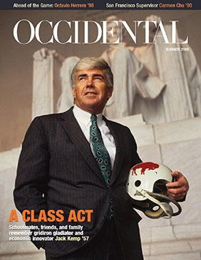 A man in a navy suit holding a football helmet in front of t