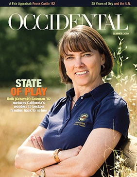 A woman in a blue polo shirt stands smiling in a field with 