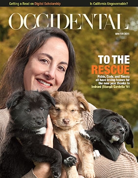 A smiling woman holds three small puppies