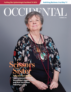 A woman in a colorful shirt sits before a grey background. C