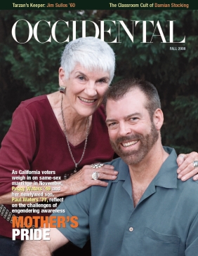 A woman with white hair in a red shirt hugs a bearded man in