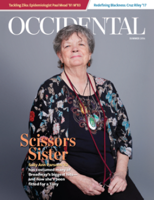 A woman in a colorful shirt sits before a grey background. C