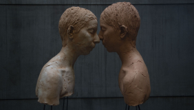 color image of two sculptural busts in profile, with faces touching