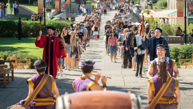 Two long lines of students walking up to Thorne Hall on campus for Convocation